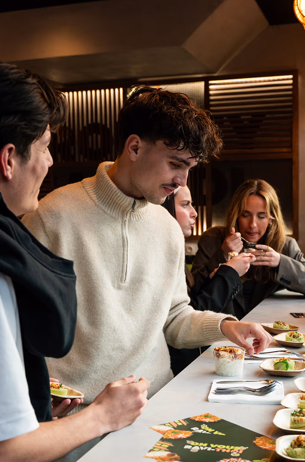 Dégustation de plats en groupe dans un restaurant thaï Krousty Sabaïdi avec ambiance chaleureuse et éclairage tamisé.