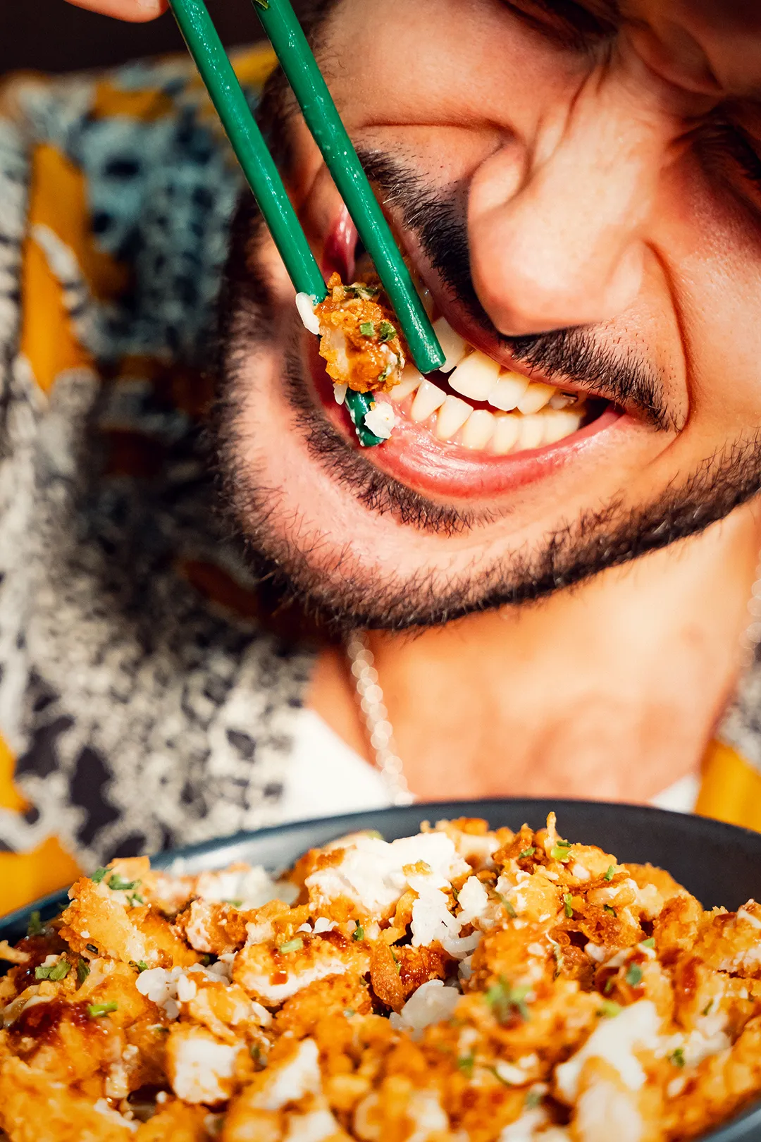Plat asiatique servi dans une assiette noire : riz sauté au poulet croustillant, oignons frits, coriandre fraîche et sauce signature, avec une présentation soignée et appétissante.