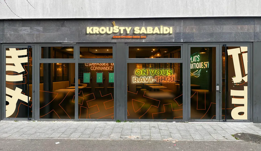 Salle du restaurant Krousty Sabaïdi à Rouen – Petit-Quevilly présentant des bornes de commande murales, un comptoir moderne et des enseignes lumineuses invitant à passer commande.