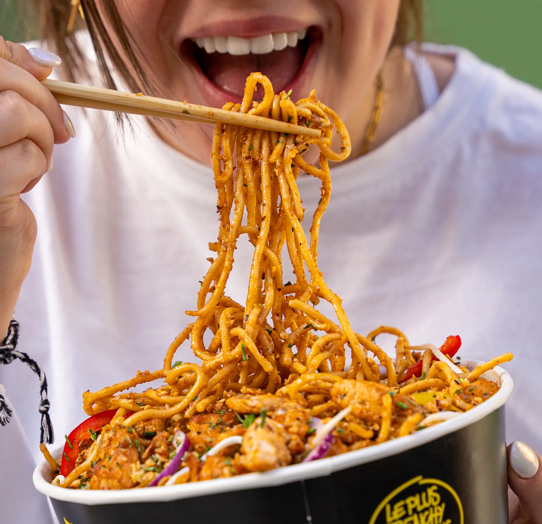 Personne qui mange un padthaï au wok de Krousty Sabaïdi avec des baguettes.